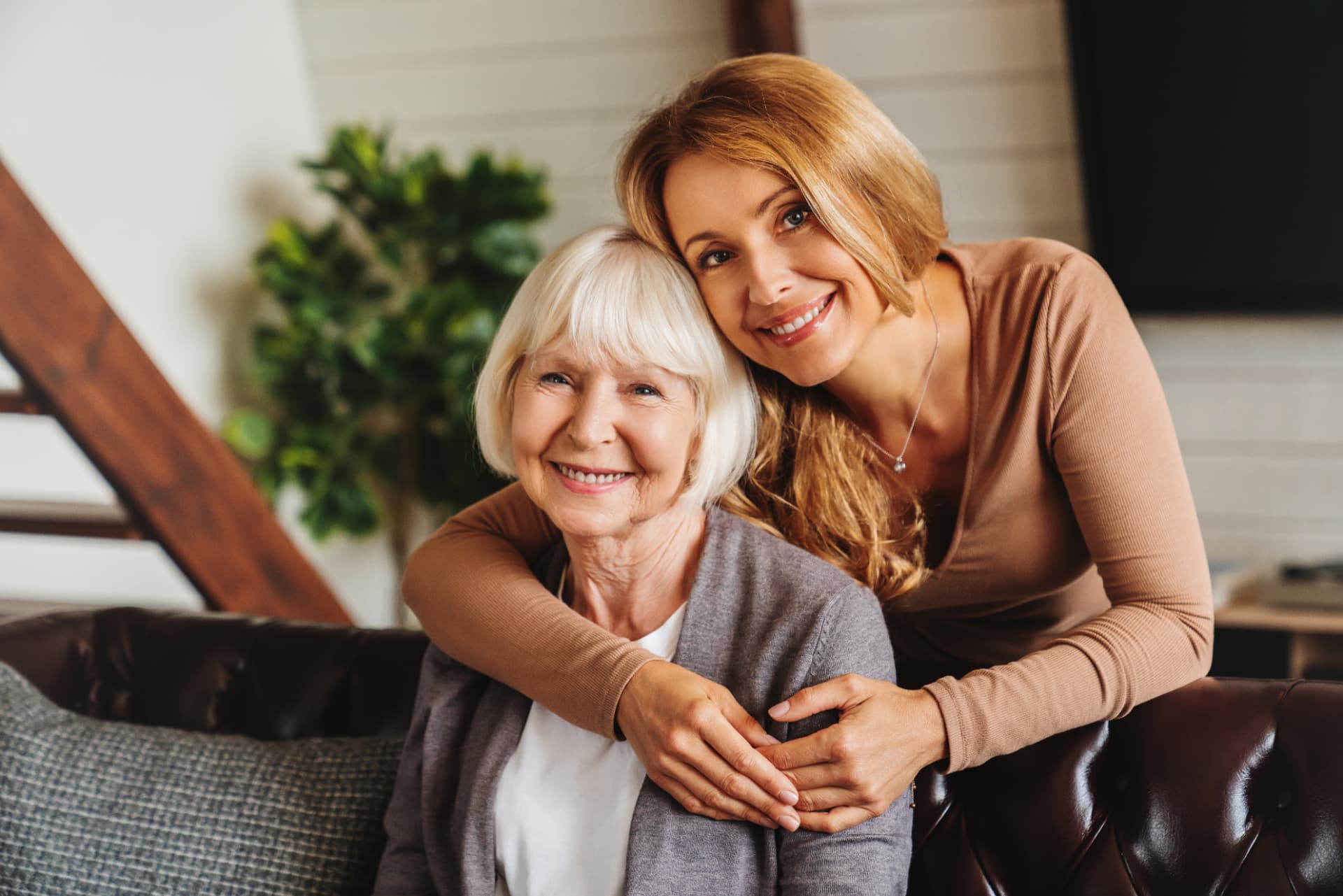 An adult daughter embracing her senior mother at home